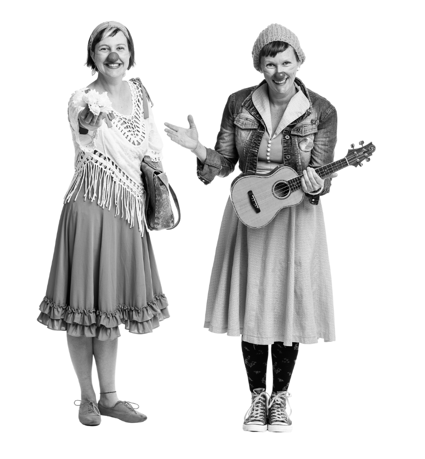 Deux femmes avenantes costumées en vêtements amples. Elles portent des nez de clown. L'une tend la main, l'autre tient un ukulele